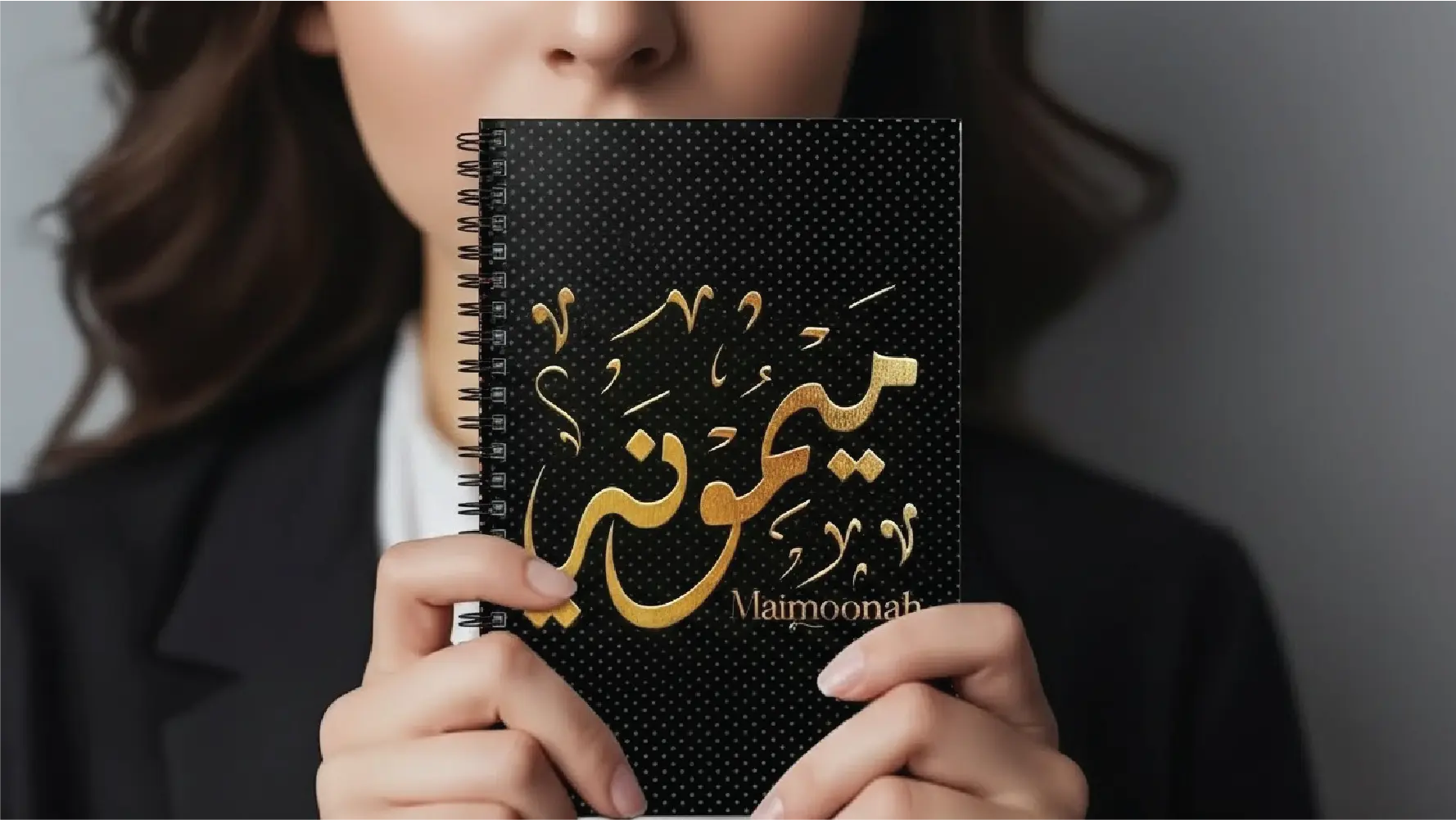 Life style image of model holding spiral notebook with Maimoonah written in Arabic Diwani Calligraphy - binmahmood